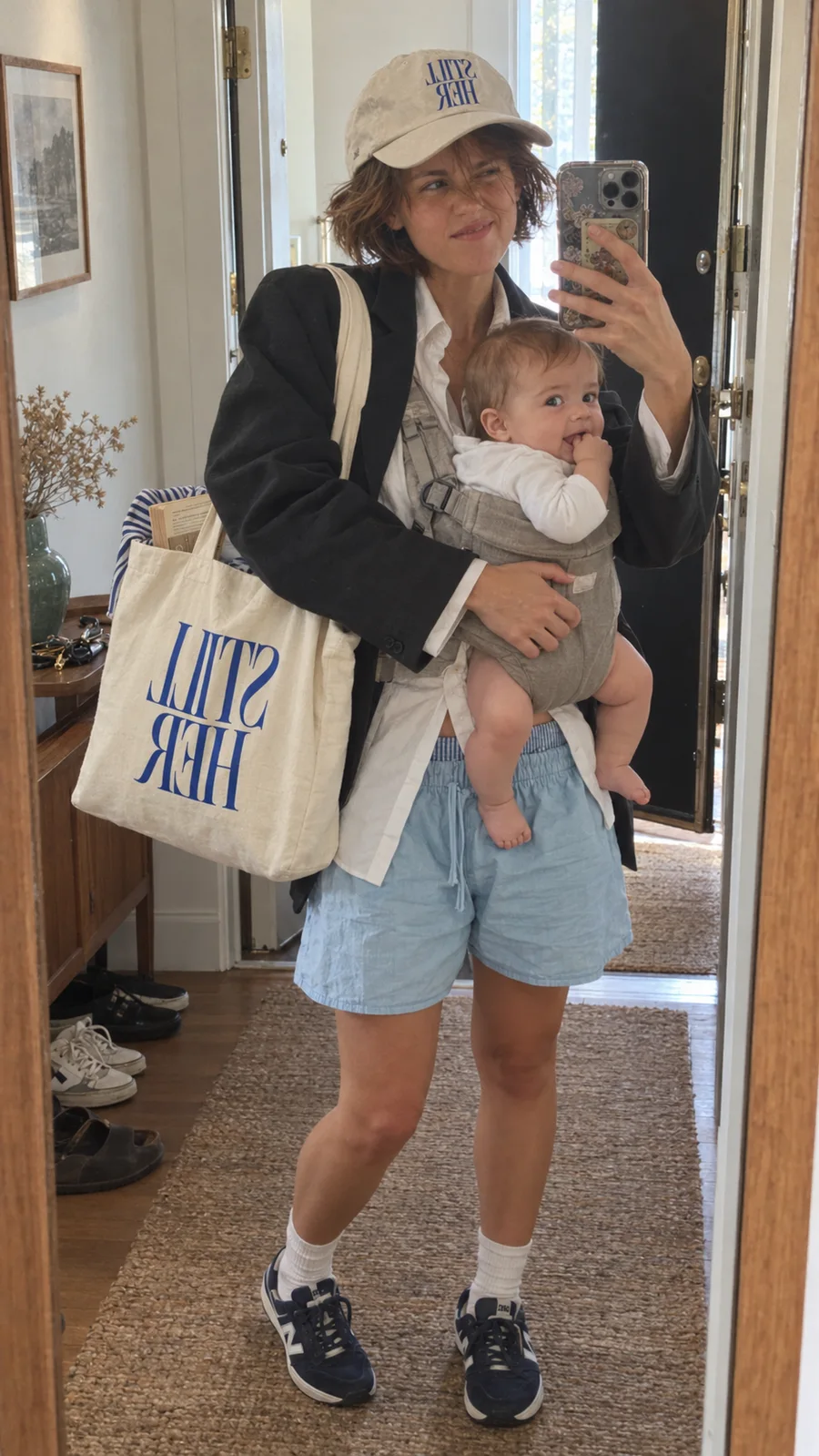 Mother taking a playful mirror selfie in a STILL HER cap and tote